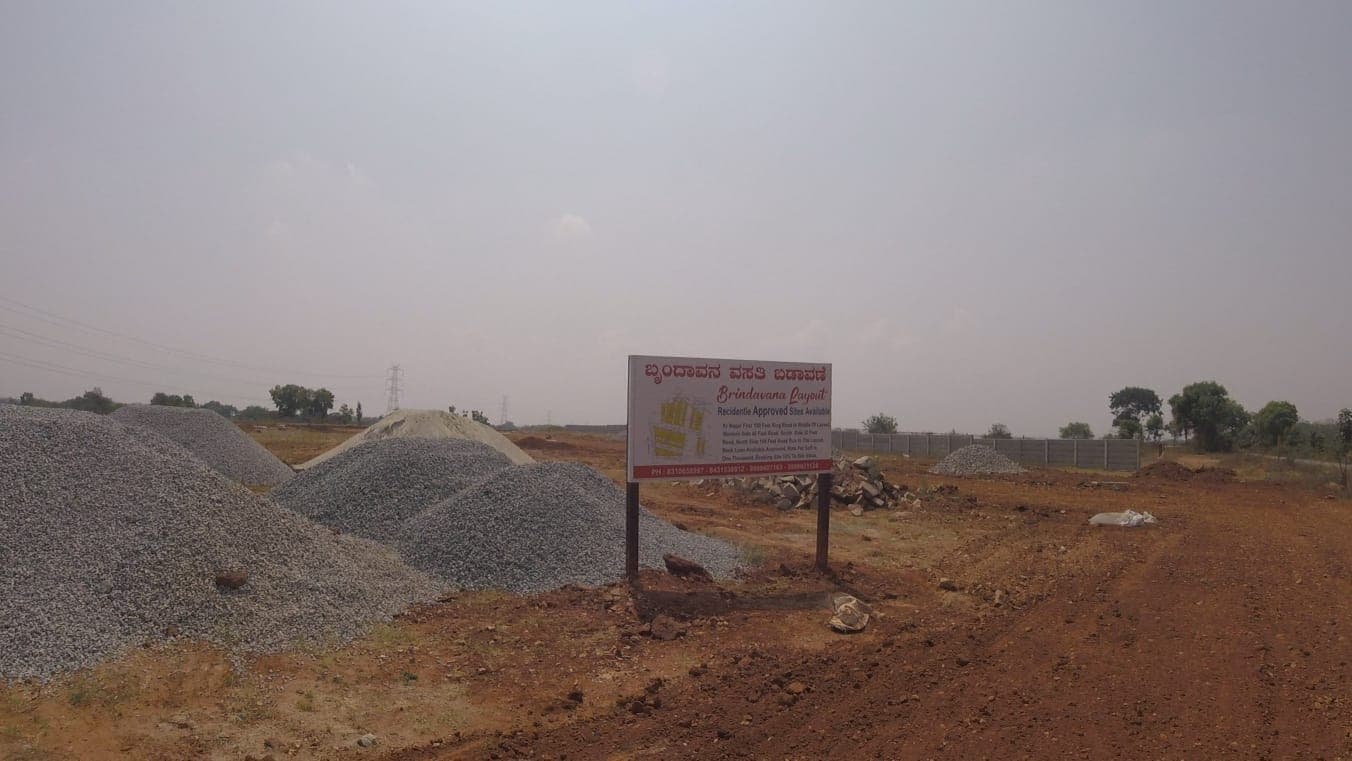 Brindavana Layout site board beside stacks of road metal